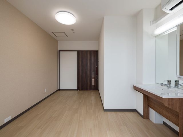 洗面台付きの居室 居室   木目調の扉と明るい床が印象的な、すっきりとした居室です。洗面台が備わっており、日々の身支度がしやすい空間です。