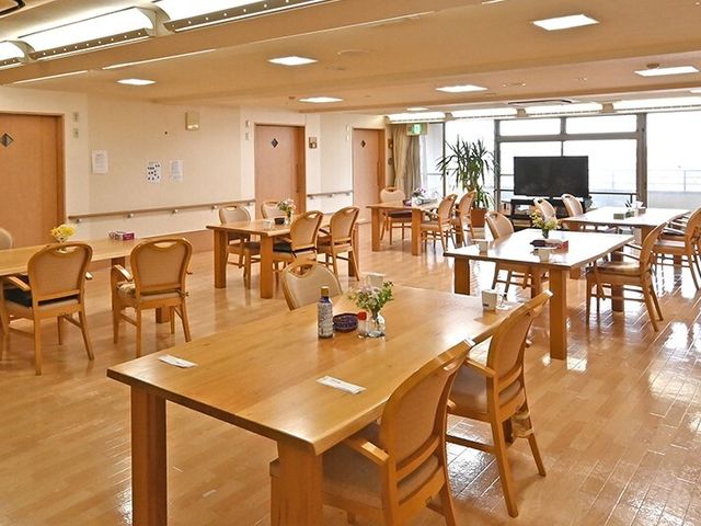 明るい共有スペース 食堂 広々とした食堂は木製のテーブルと椅子で温かみのある雰囲気を醸し出しています。明るい窓辺には、居心地のよい休憩スペースもあります。