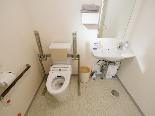手すり付きトイレと洗面台 トイレ 手すりが設置されたトイレと、使いやすい配置の洗面台があります。利便性を重視し、皆様の快適な日常生活を支える環境が整っています。
