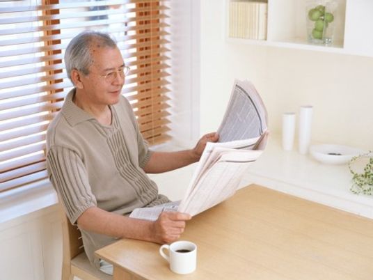 明るい部屋で新聞読む人