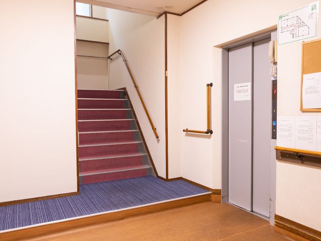 階段とエレベーターのある廊下 廊下 手すりが配備された階段と、待ち時間を減らすためのエレベーターを備えたアクセスしやすい動線です。