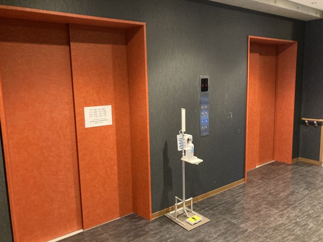 落ち着きある廊下 廊下 エレベーターの前に消毒液が配置され、感染対策がしっかりとされています。落ち着いたデザインが特徴の施設です。