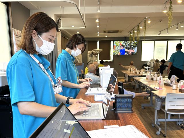 スタッフ風景の室内 休憩室 スタッフが笑顔で活動する様子が見られます。明るく広々とした空間が広がっています。