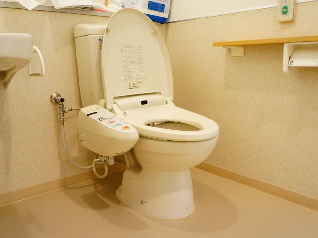 手すり付きの洋式トイレ 洋式トイレ 手すり付きで安全性を考慮したトイレです。快適な水周り環境が整っており、働く環境への配慮が感じられます。