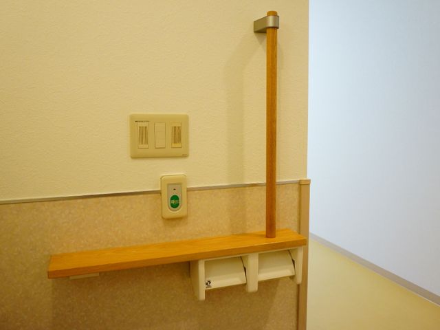 手すりと非常ボタンの廊下 トイレの緊急コール 廊下にはしっかりとした手すりが設置され、安全を考慮した非常ボタンも整っています。利用者の移動をサポートする環境です。