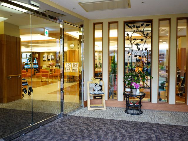 照明付きエントランスの風景 入り口 開放感のあるエントランスは、訪れる方々を暖かく出迎えるデザインになっており、植物に囲まれた落ち着いた雰囲気です。