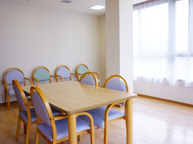 清潔なダイニングテーブル 集会室の片隅 窓から自然光が差し込むダイニングです。ゆったりとした椅子が並び、共に食事を楽しむ空間が整っています。
