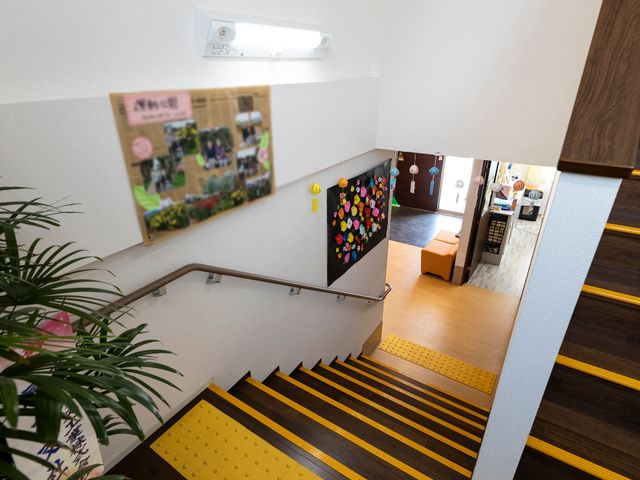 明るい廊下と階段 階段 掲示物が飾られた安全な歩行空間。この廊下は日々のコミュニケーションに彩りを与えています。