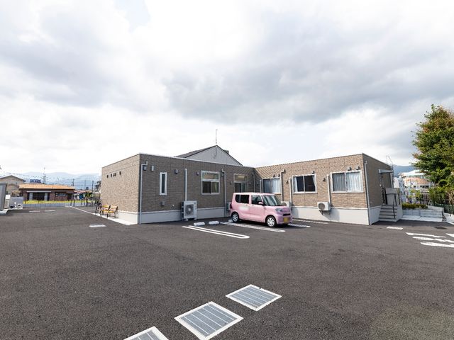 広々とした駐車場の施設外観 中庭 ゆとりある駐車スペースを確保した建物の外観です。来訪者の利便性も考慮した設計になっています。
