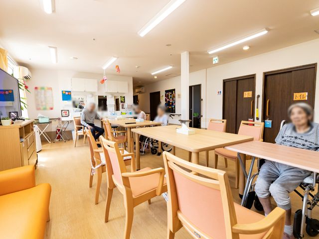 共用スペースの居心地良い様子 リビング リラックスして過ごせる食堂で、利用者が穏やかな時間を過ごしています。木のテーブルと椅子が温かみのある雰囲気を醸し出しています。