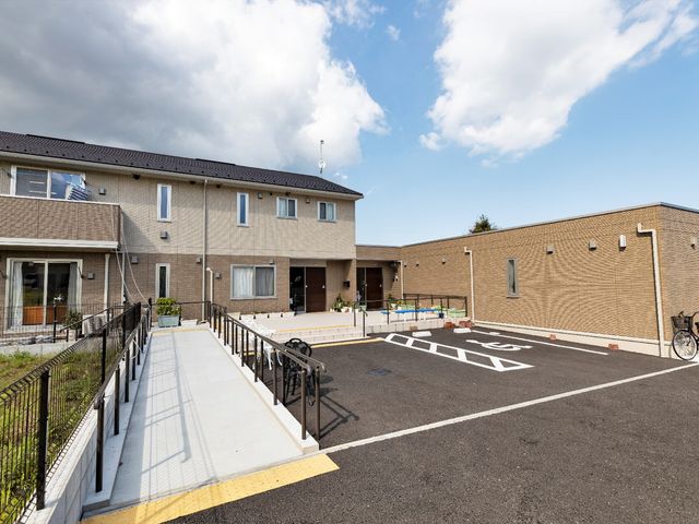 建物外観と駐車場 中庭 清潔感があり、明るい印象の外観です。バリアフリー設計のアプローチを備え、快適な職場環境を提供しています。