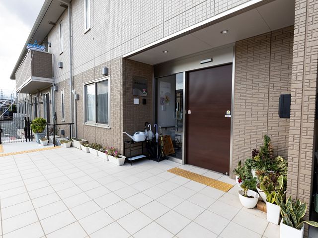 エントランスの明るい外観 玄関 親しみやすい装飾が施されたエントランスです。転倒防止のための滑り止めマットが敷かれ、安全に配慮されています。
