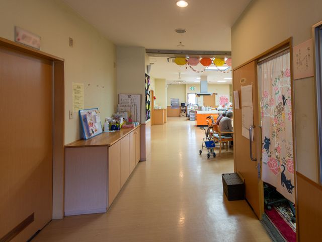 廊下と食堂入口 心地よい光が差し込むダイニングルームへの入口です。明るく広々としたスペースで、利用者様が食事や交流を楽しんでいます。