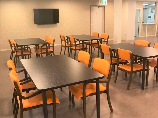 オレンジの椅子の食堂 お食事・談話スペース きれいで広々としたダイニングルームです。お食事時以外もコミュニケーションの場として、皆さんで使えるスペースです。
