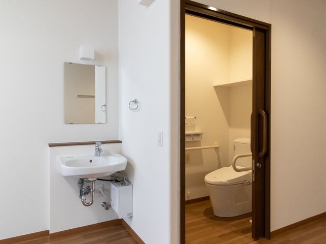 洗面台とトイレの居室 居室 手すり付きトイレと清潔感ある洗面スペースが備わっており、日々の暮らしが安心できる環境です。