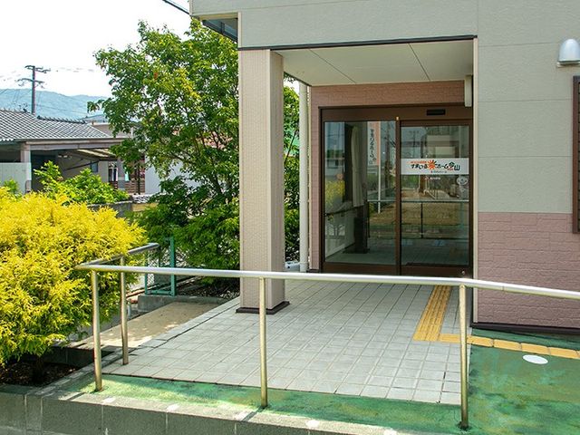 緑に囲まれた玄関 エントランス   手すり付きのアプローチがあり、段差の少ない出入口になっています。周囲に植栽があり、明るく落ち着いた印象です。