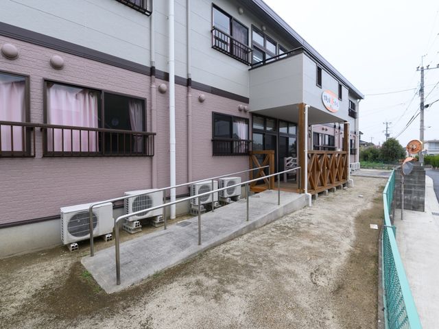 アクセスしやすい外観 玄関 手すりが設置されたエントランスは、全ての方が気軽に出入りできるよう配慮されています。明るく開放感のあるこの場所で、新しい職場の一員になりませんか。