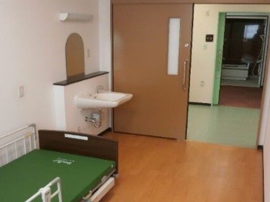 個室の洗面台とベッドの居室  