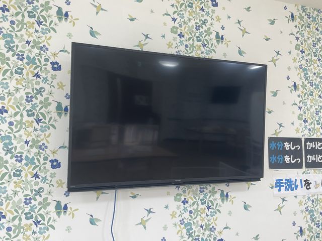 壁掛けテレビがある部屋 テレビ 色とりどりの花柄の壁が印象的な、くつろぎの場に設置された大きなテレビです。