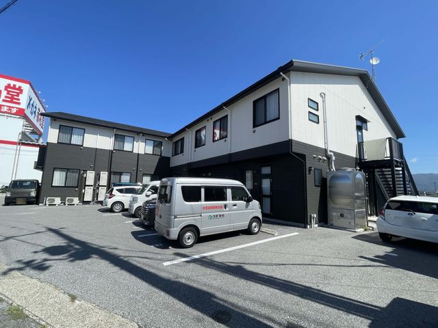 駐車場のある建物外観 外観 広々とした駐車場があり、車でのアクセスが便利です。シンプルで落ち着いた色合いの建物が特徴です。