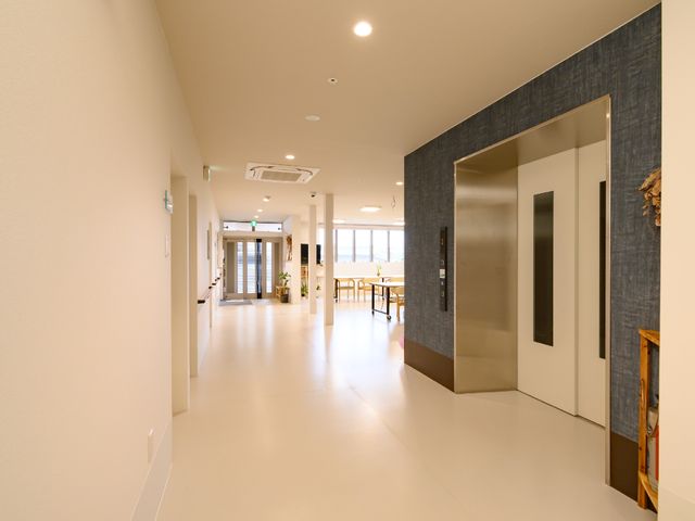 広々とした明るい廊下 廊下 床が光を反映し、明るく清潔感のある通路が広がっています。エレベーター横のスペースでは、リラックスしながら交流が楽しめそうです。