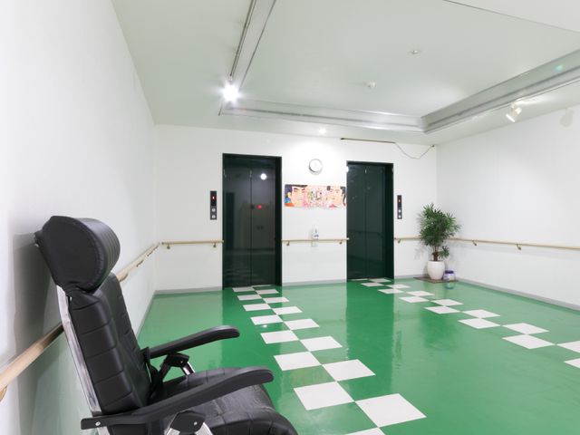 廊下の床がチェック模様 エレベーターホール ゆったりとした空間の廊下です。壁には手すりが設置されており、歩行時の安全を支えています。