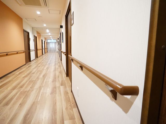 手すり付きの明るい廊下 廊下 幅広の手すりが設置され、歩行が不安な方も安心して移動できる設計になっています。明るく開放的な廊下は、快適な勤務環境を提供します。