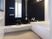 白と黒のシックな雰囲気の浴室である。広めのシャンプー台が取り付けられている。壁には手すりが設置されている。