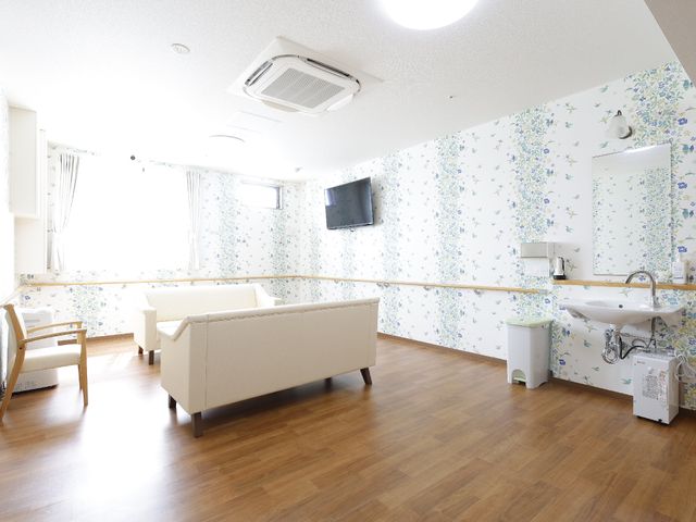 リビングの明るい空間 共有スペースE 床から天井まで光が差し込むリビングです。柔らかいソファーが安らぎの時間を提供しています。