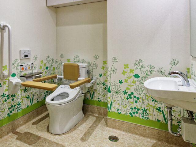 緑の飾りがあるトイレ トイレ 安全設計の手すりがついたトイレです。明るく清潔感が感じられる空間です。