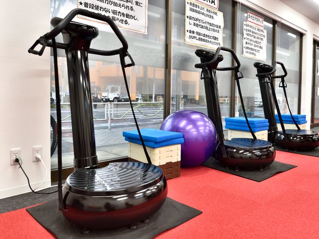 トレーニング機器とボール 床は赤で、トレーニング機器やバランスボールが置かれ、機能訓練に適した空間が整えられています。全身の運動ができるように工夫された環境です。