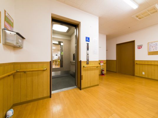 壁面には手すりが取り付けられている。エレベーター内部には鏡があり、出入り口横には車いすで使用が可能なマークがある。