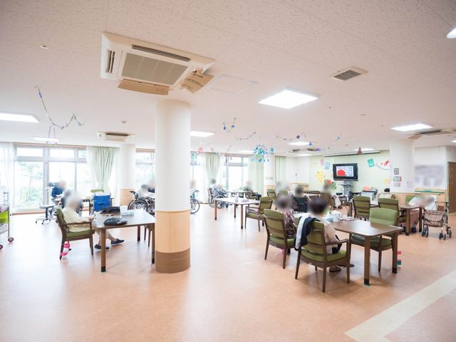 共有スペースの落ち着いた様子 共有スペース 天井が高く開放感のあるラウンジで、利用者の方々が憩いのひと時を過ごしています。リラクゼーションや交流が図れる、ゆとりある空間です。
