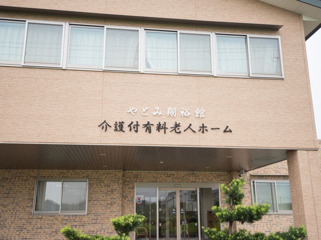 温かみのあるエントランス 外観 優しい色調の壁が印象的なエントランスです。きれいに手入れされた緑もあって、訪れる方を温かく迎え入れます。