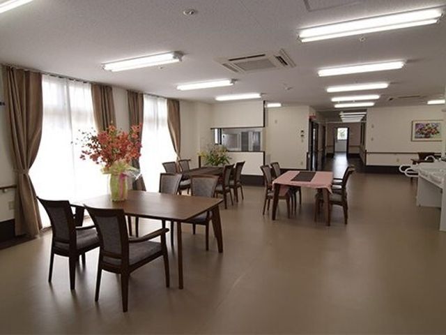 広々とした明るい食堂 共有スペース 広々とした食堂には、木目調のテーブルと椅子が並び、窓から自然光が差し込む明るい環境が広がっています。花の装飾が心地よい雰囲気を醸し出し、居心地の良い空間を提供しています。