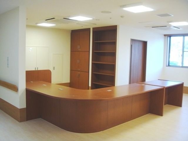温かみのある受付カウンター フロント 落ち着いた色合いのフロントは、訪れる方々を安心感で迎えます。十分な収納スペースも備えています。