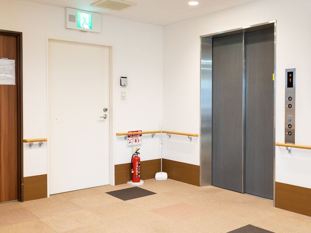 広々とした明るいエレベーター前 エレベーター 利便性を考え抜かれたエレベーター周りは、ゆとりのある設計で、皆様の移動をサポートしています。手すりも設置されており、安全に配慮されています。