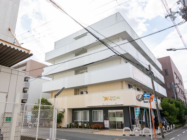 白い建物のエントランス 外観 清潔感のあふれるエントランスが迎えてくれる施設です。明るい雰囲気の中、入居者様の日常が始まります。