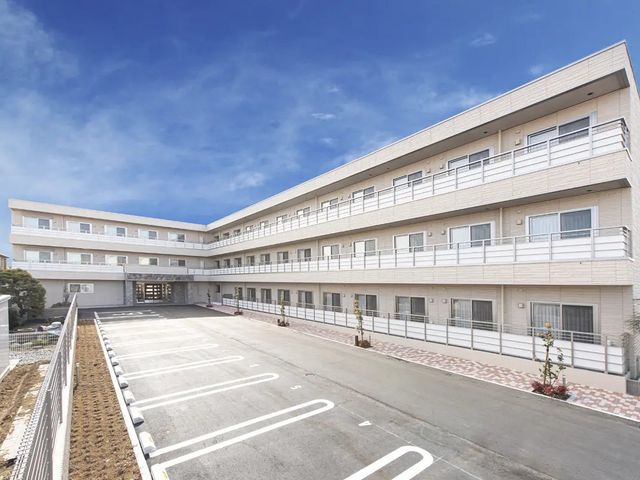 施設外観 外観   青空の下に、白を基調とした落ち着いた建物が広がっています。駐車スペースも見え、出入りしやすい印象です。