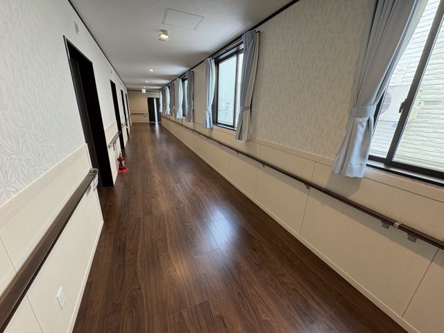 長い木目調の廊下 廊下 大きな窓から自然光が入る明るい廊下です。車椅子でも移動しやすい幅を確保しています。