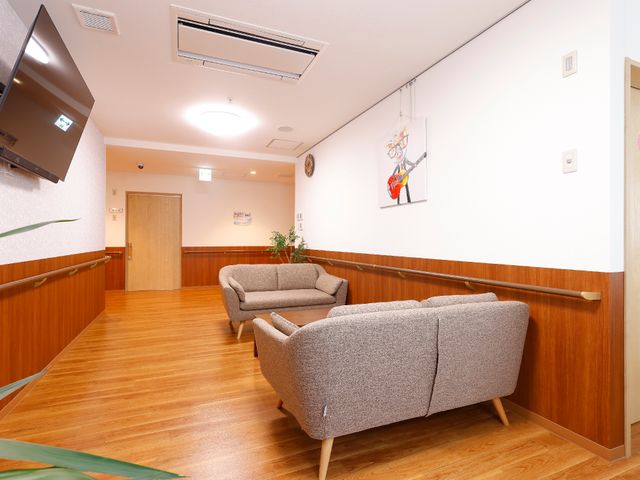 清潔な廊下の休憩スペース 廊下 広々とした廊下に配置されたソファは、待ち時間などに一息つくのに適しています。木の温もりが感じられる設えが、落ち着いた雰囲気を醸し出しています。
