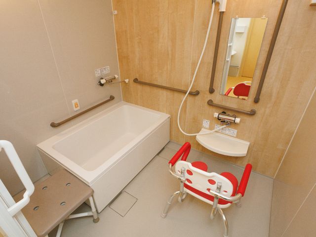 バリアフリー設計の浴室 浴室 安全に配慮された広々とした浴室で、手すりや椅子が整備され、快適な入浴が支援されます。