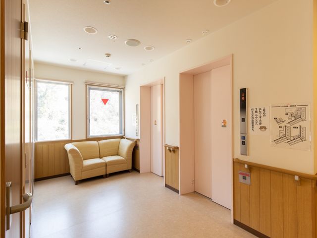 明るい廊下のコーナー エレベーター ゆったりとしたソファが設けられた角の休憩スペースです。自然光が差し込む明るさが魅力的な場所で、心地よい休息をとることができます。