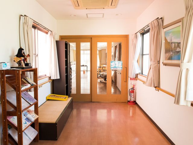 光が差し込む居室入口 休憩スペース 温かみのある居室入口は、開放的な造りで明るい印象を与え、快適な生活空間へと招いています。