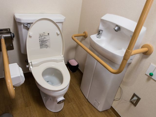 バリアフリートイレ設備 トイレ 安全手すり付きの清潔な洋式トイレです。移動や立ち座りが楽になるよう配慮されており、働く環境にも配慮が感じられます。