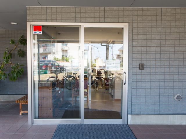 清潔で開放的なエントランス 玄関 ガラス扉越しの通りを眺めながらくつろげる、明るいエントランスです。待ち合わせに便利なベンチが設置されています。