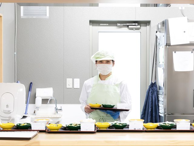 厨房で配膳をする様子 キッチン 明るく整ったキッチンで、食事の準備が進められています。衛生管理に気を配った環境です。
