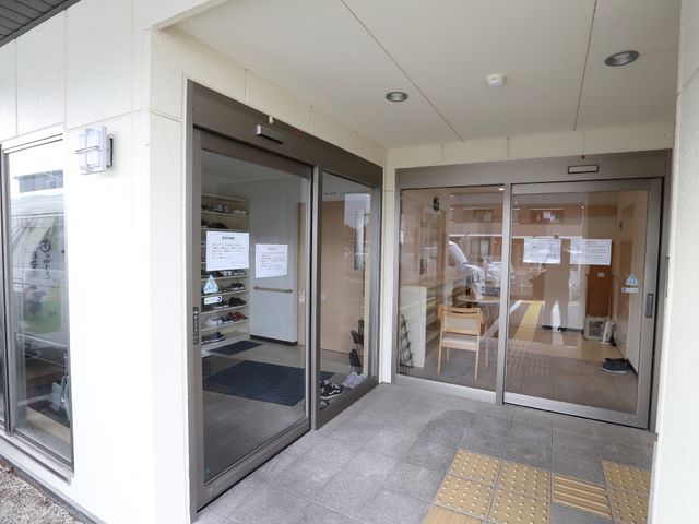 明るいエントランスの様子 玄関 ガラス張りのエントランスは開放感があり、スタッフの明るい表情が迎えてくれます。利用者様が快適に過ごせる環境が整っています。