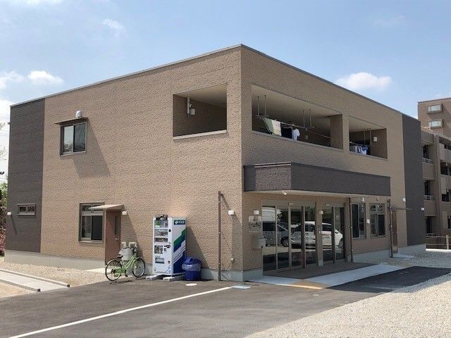 茶色の建物の外観 外観 広々とした駐車場があり、アクセスの良い立地の建物です。清潔感のあるエントランスが、訪れる方を穏やかに迎え入れます。