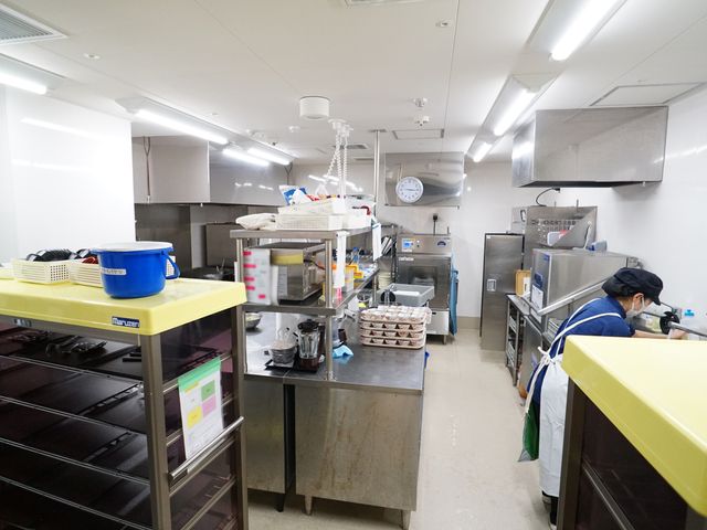 清潔なキッチンの風景 キッチン 整理された設備の中で、調理スタッフが食事の準備に集中しています。衛生的な環境で、健康的な食事が提供されております。